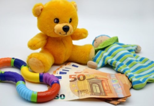 Un osito de peluche y juguetes alrededor de unos billetes de 50 euros